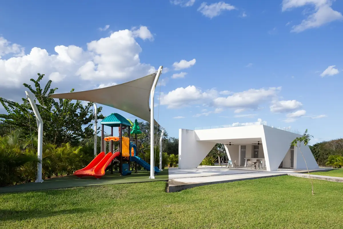 Juegos infantiles de Blanca Residencial con resbaladilla, estructura de colores y cubierta de sombra.